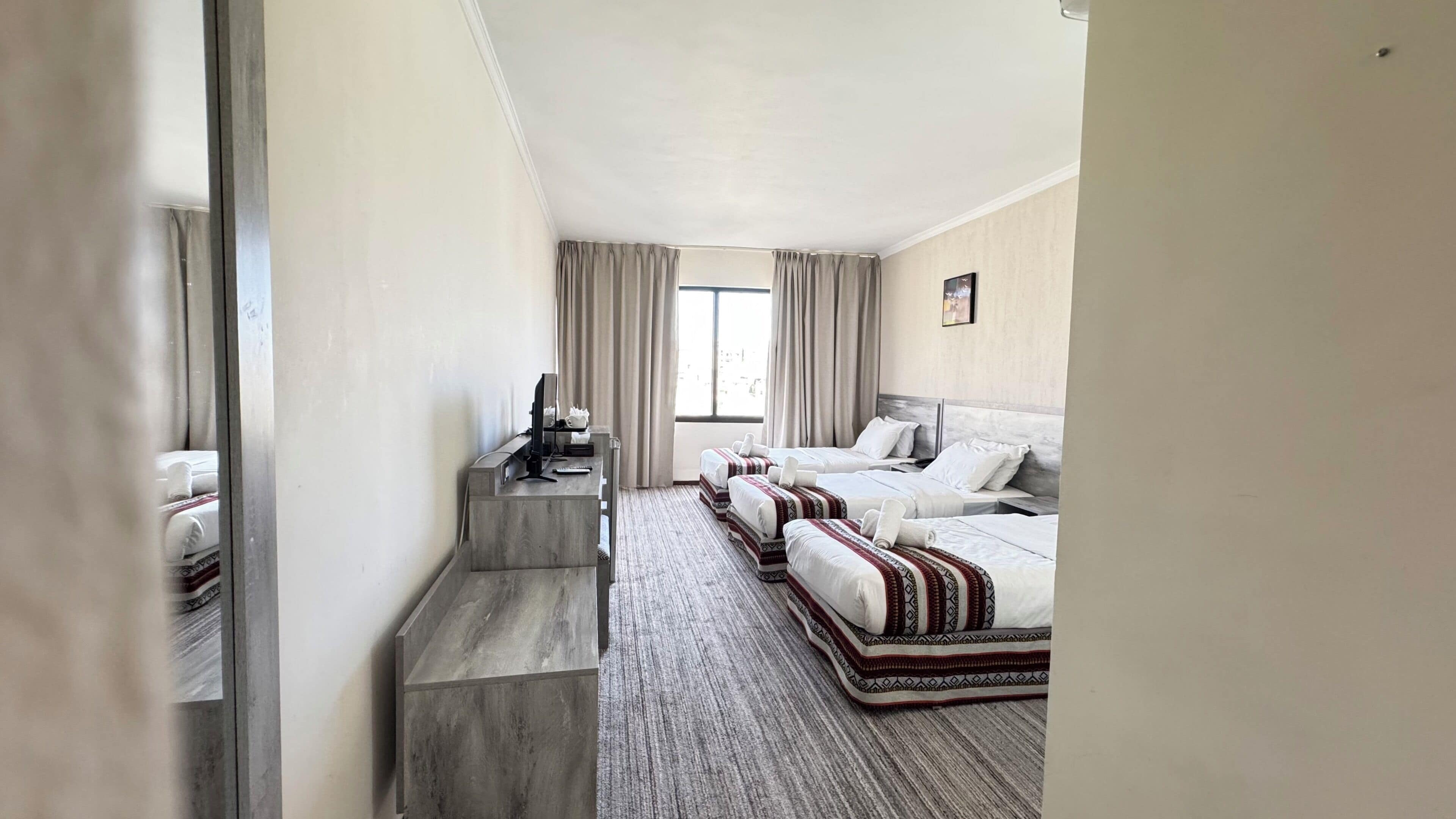 A hotel room with a bed, a desk, a chair, a window, and a view of the outside.