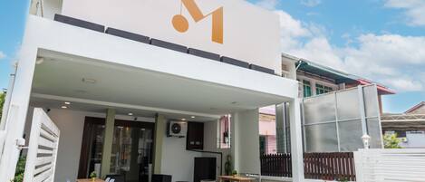 Un edificio moderno con un logotipo destacado, zona de estar al aire libre y un patio cubierto.