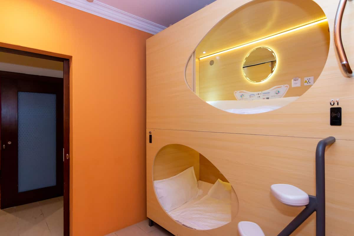 A modern hotel room with a circular bed design, a visible door, and a control panel.