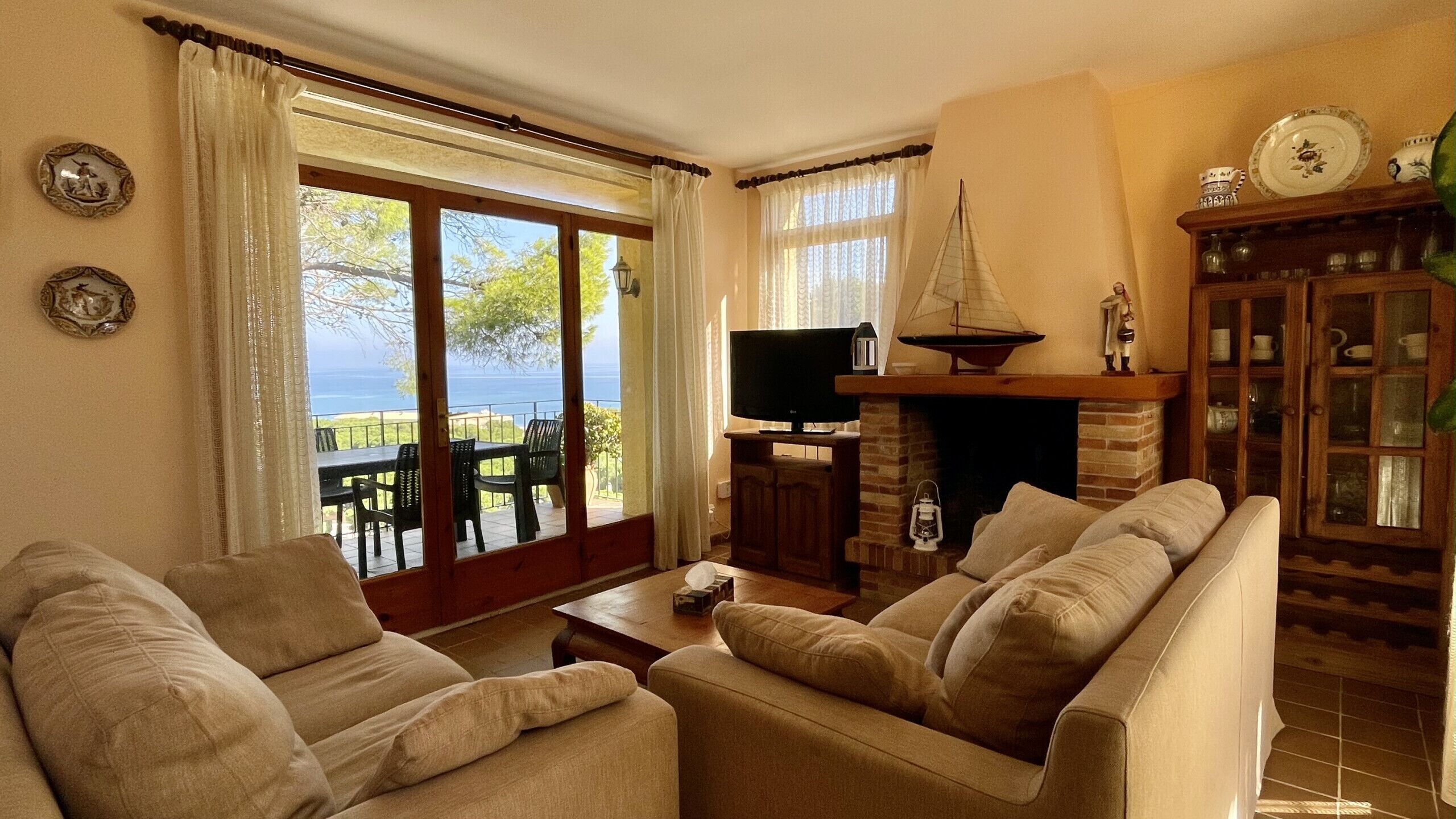 Un salon comprenant un canapé, une télévision, une cheminée et une vue sur la mer.
