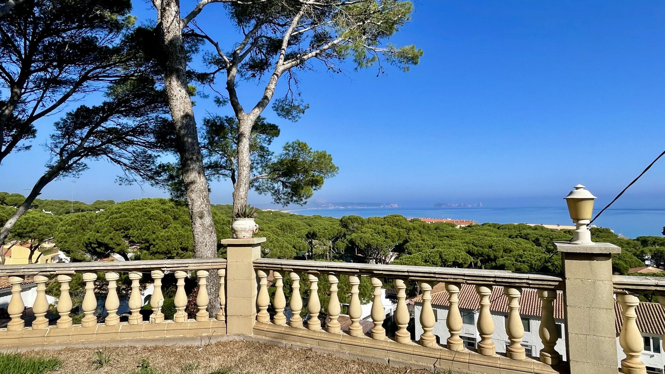 Une vue sur la côte, avec une balustrade en pierre, des arbres et un ciel dégagé.