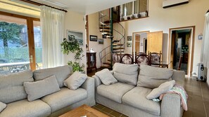Un salon comprenant deux canapés, une table basse, un escalier et un coin repas.