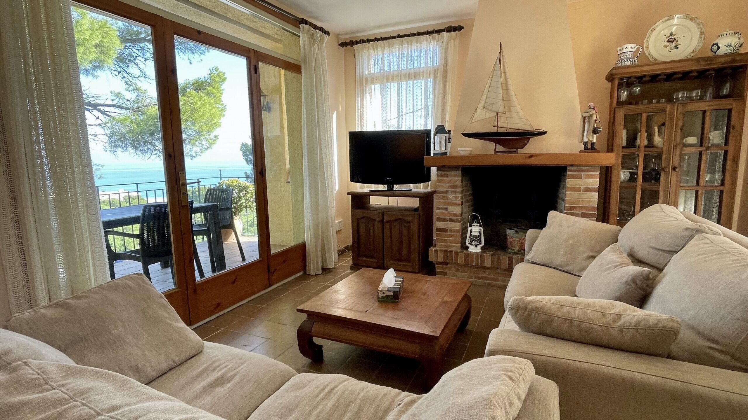 Un salon avec une cheminée, un téléviseur et une vue sur la mer.