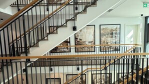 A multi-level interior with a staircase, a fire alarm, and a green exit sign. - Romantik Hotel Das Lindner (Bad Aibling)