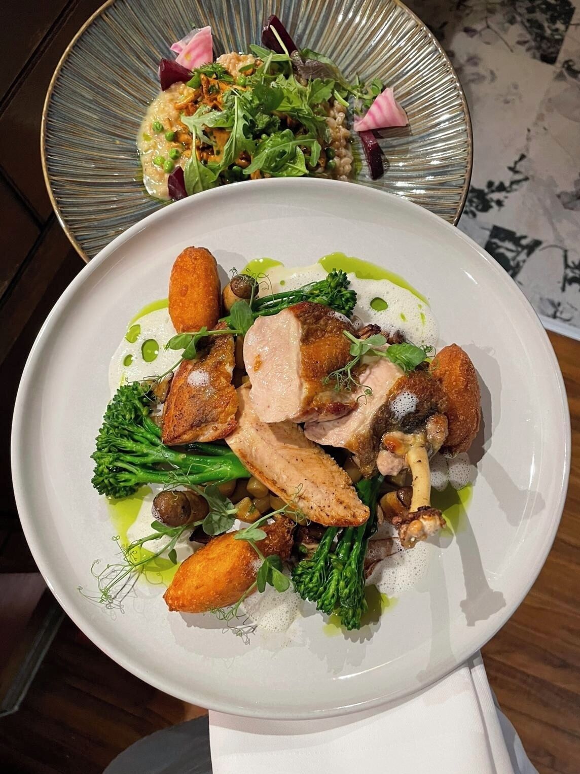 A plate of food with various vegetables and a piece of meat, possibly chicken, on a white plate.