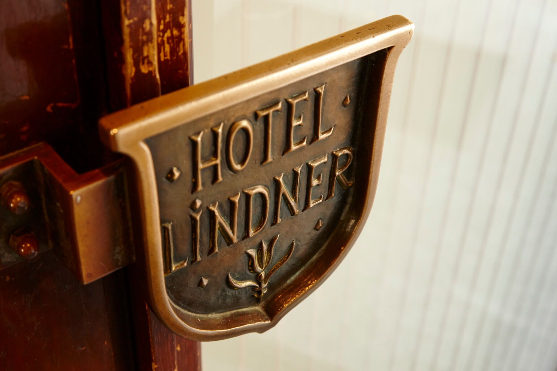 A brass hotel sign with the name "HOTEL LINDNER" engraved on it.
