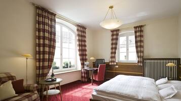 A hotel room with a bed, a desk, a chair, and a window with curtains.