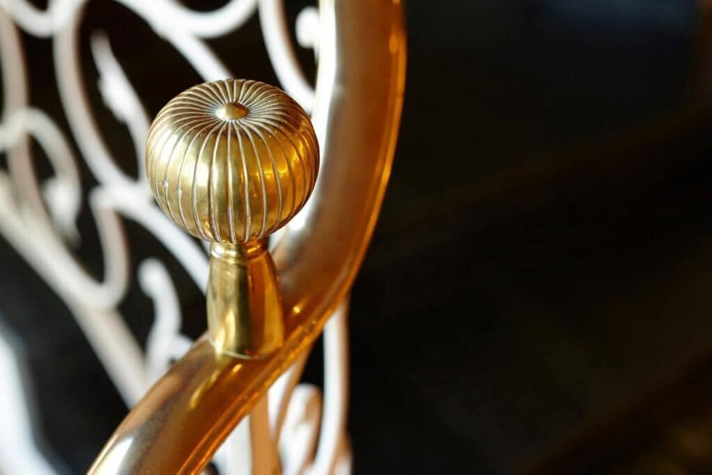 Primer plano de un objeto dorado, con nervaduras y forma esférica, unido a una estructura metálica curvada.