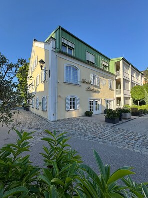 A hotel with a green roof, multiple windows, and a cobblestone courtyard.
