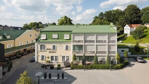A hotel with a green roof, multiple floors, and a courtyard with outdoor seating. - Romantik Hotel Das Lindner (Bad Aibling)
