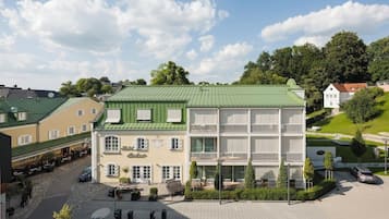 Hotel features a traditional European design with a central entrance and outdoor seating areas.