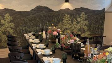 Ein langer Esstisch mit Stühlen, gedeckt mit Tellern, Tassen und einer floralen Tischdekoration.