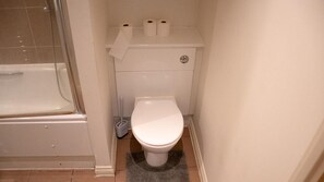 A bathroom with a toilet, a shower, and a toilet paper holder with two rolls. - Cosy One-bed Apartment in Central London (London)