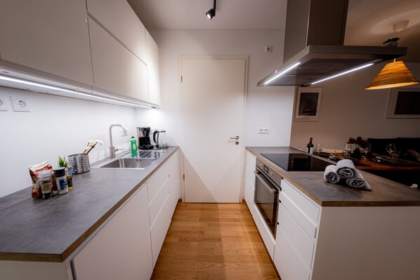 Una cocina moderna con armarios blancos, encimera de madera, horno empotrado y pileta de acero inoxidable.