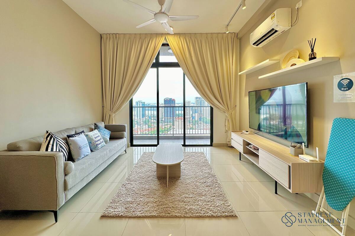 A modern living room with a sofa, TV, and a balcony with a city view.