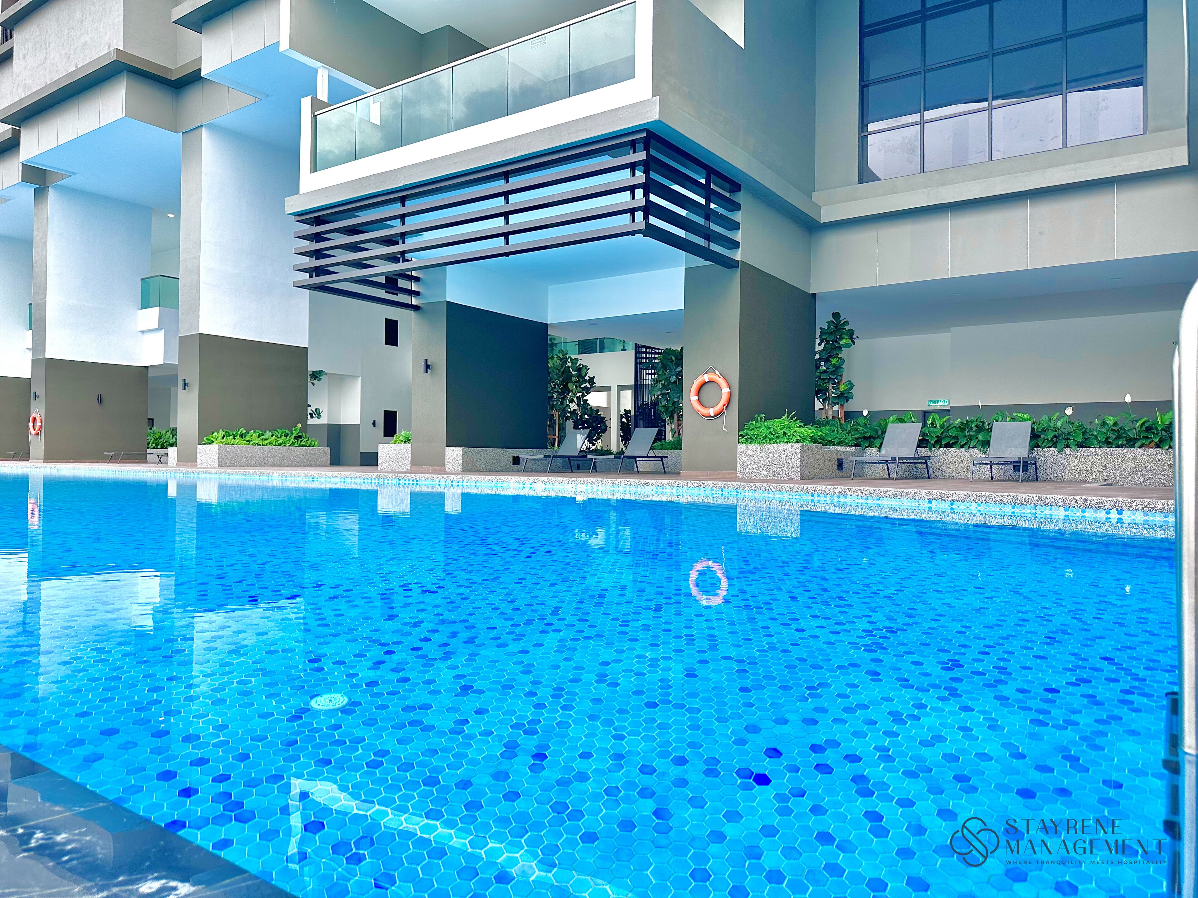 Una piscina de diseño moderno, rodeada de sillas de descanso y un flotador en la pared.