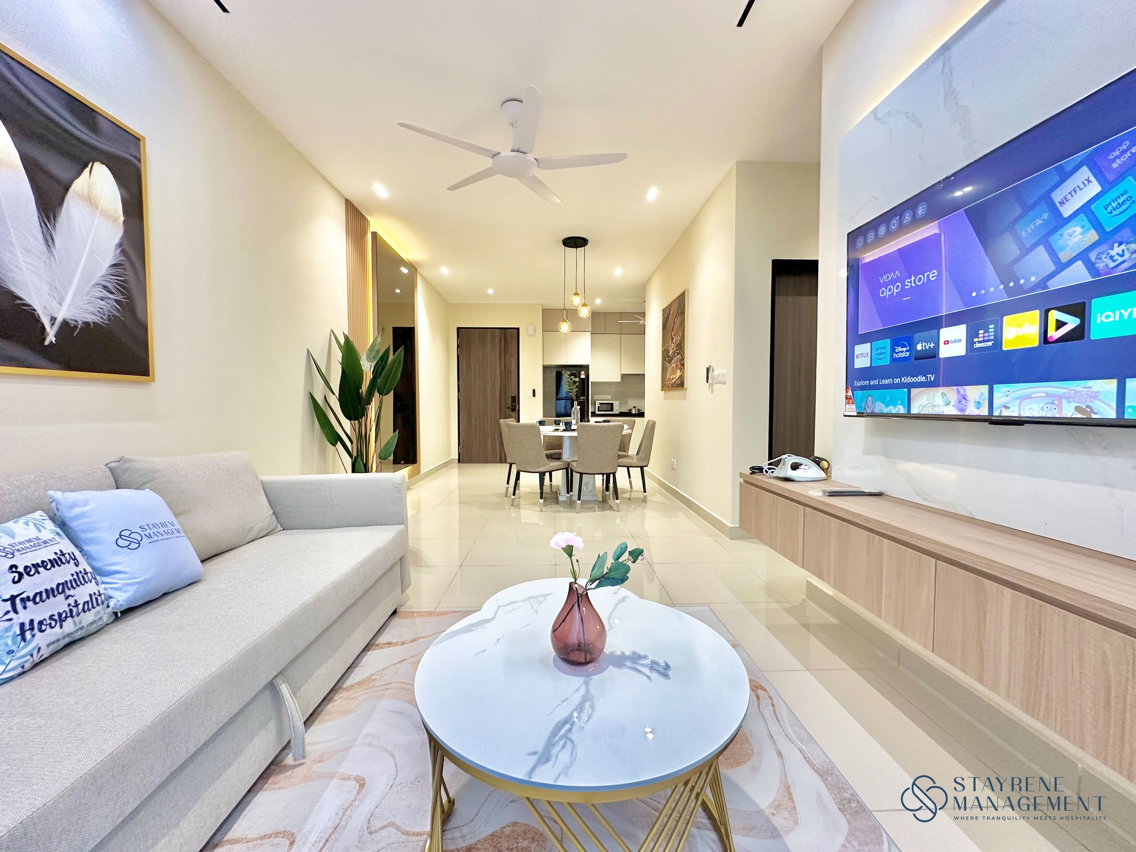A modern living room with a sofa, coffee table, and a TV displaying various streaming services.