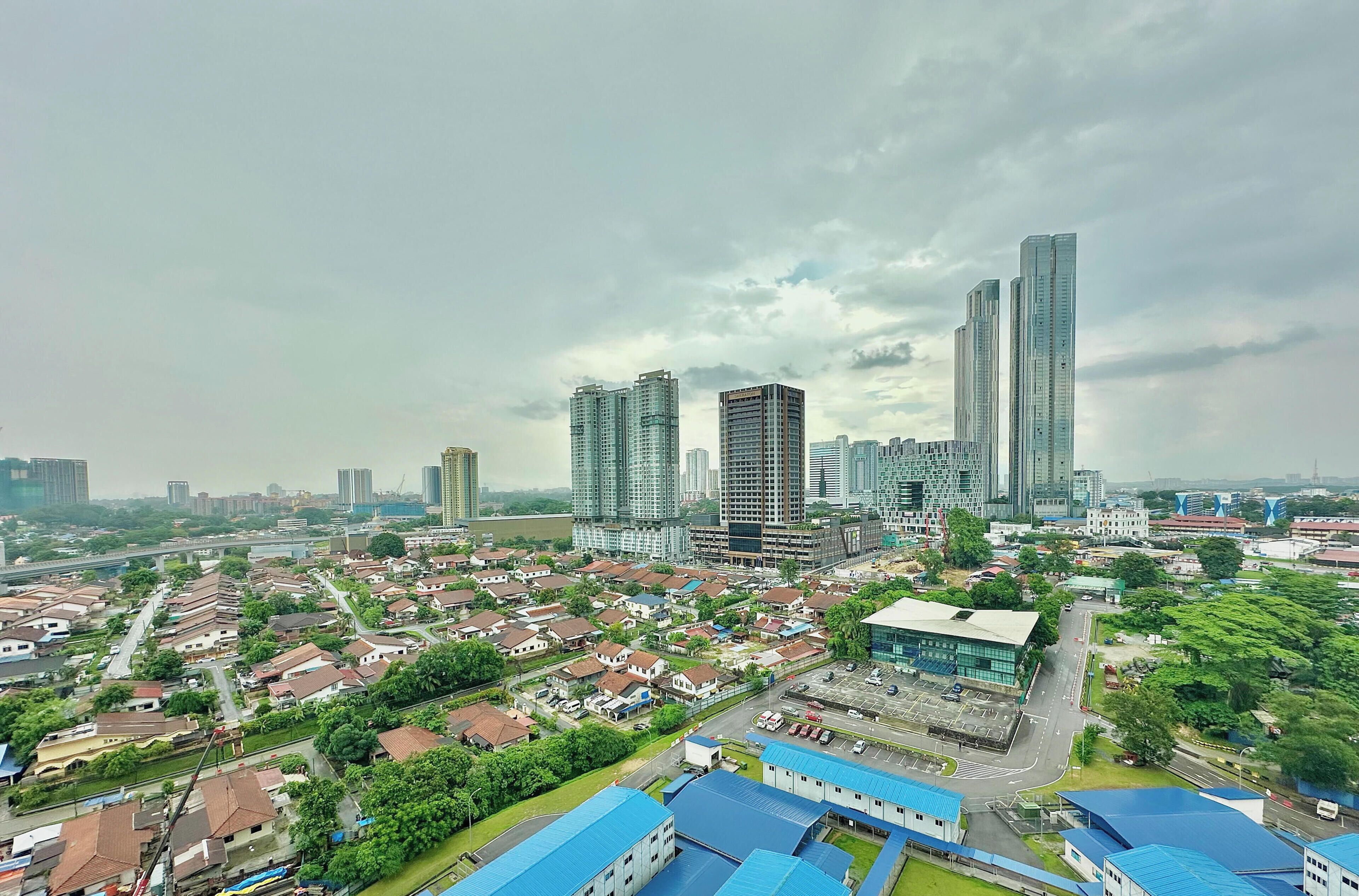 A cityscape with high-rise buildings, a mix of residential and commercial areas, and a large parking lot.