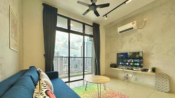 A modern living room with a blue sofa, a small round table, a ceiling fan, and a large window with curtains.