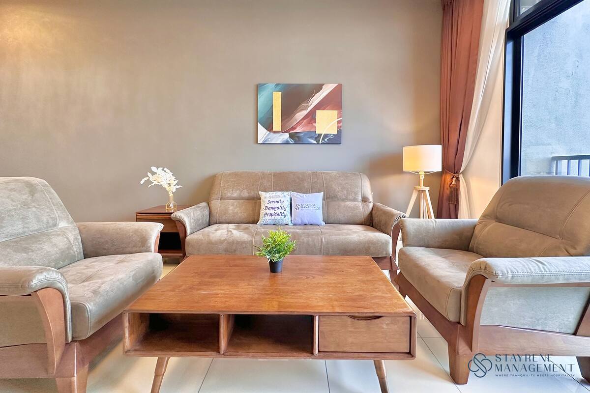 A modern hotel room with a beige sofa set, a wooden coffee table, and a painting on the wall.