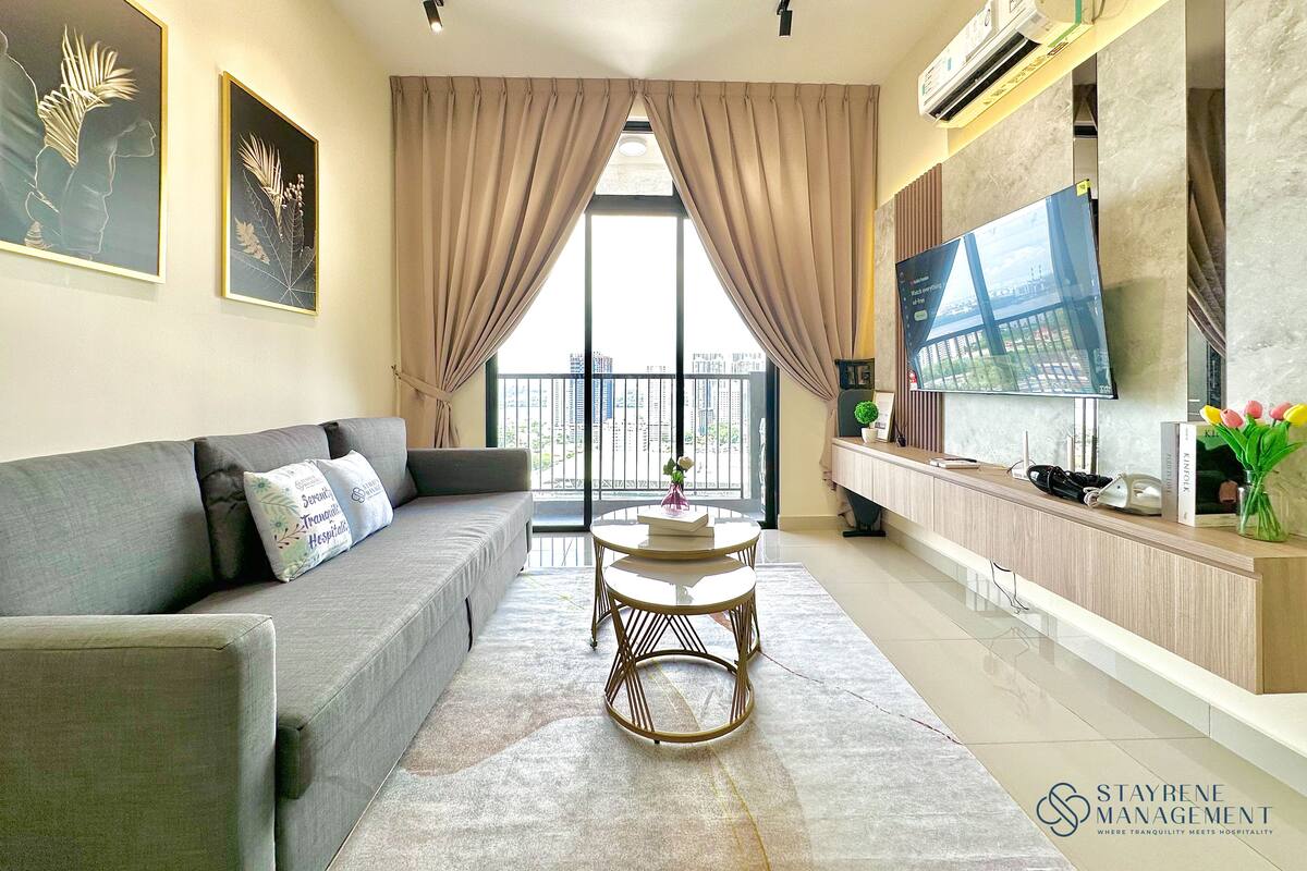 A modern living room with a grey sofa, a round coffee table, and a TV on a wooden cabinet.