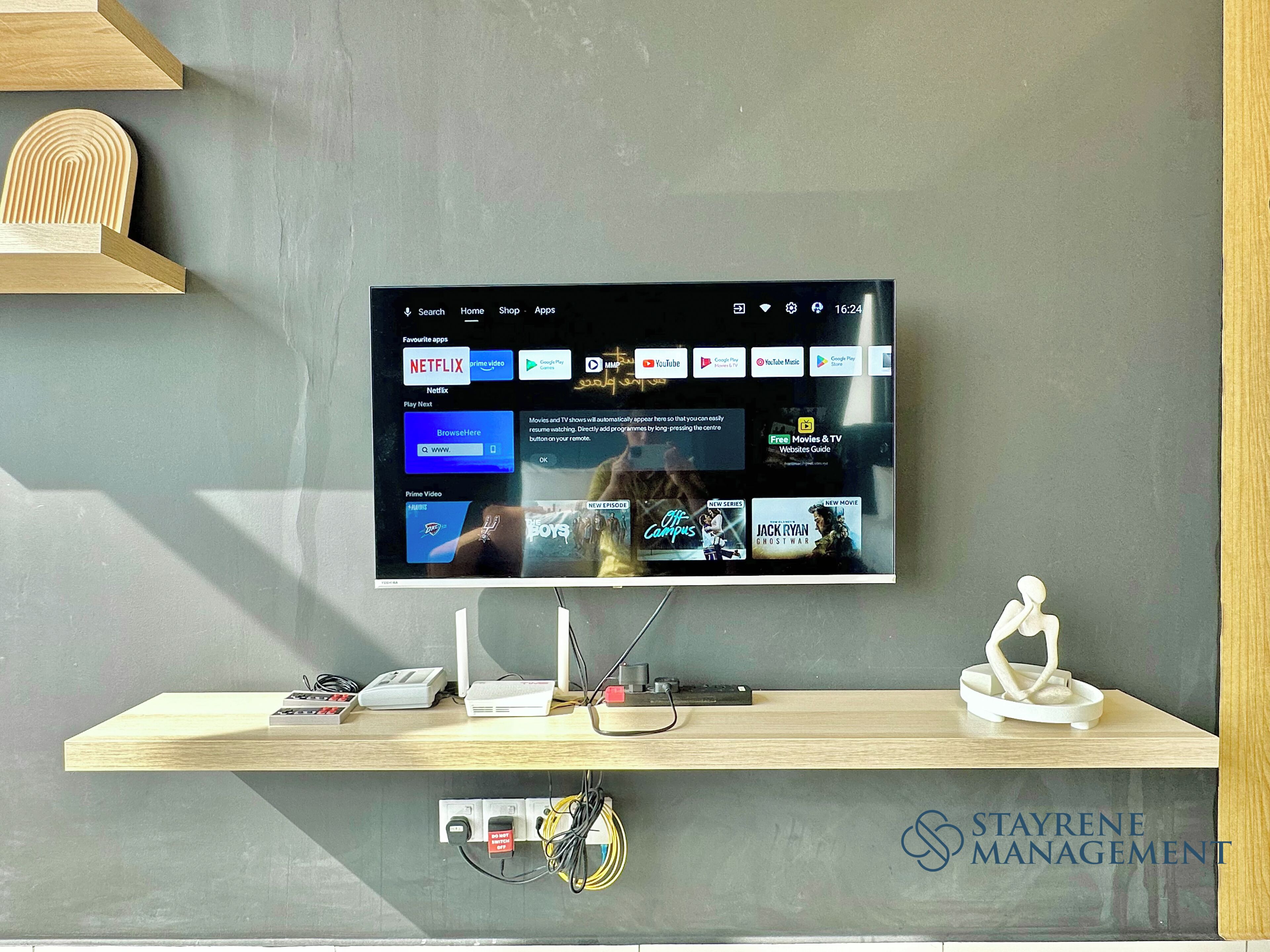 A television mounted on a wall displaying a streaming service interface with various apps and content.