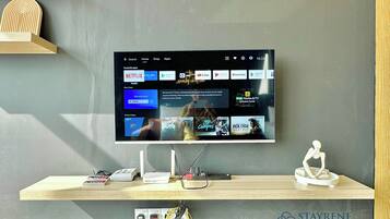 A television mounted on a wall displaying a streaming service interface with various apps and content.