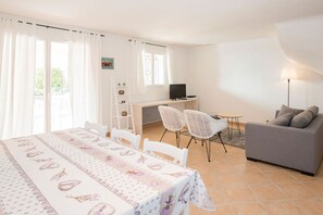 Une pièce bien éclairée, avec une table à manger, des chaises, un canapé, un téléviseur et une échelle.