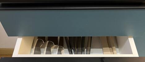 A kitchen drawer with utensils, a grater, and a spice rack.