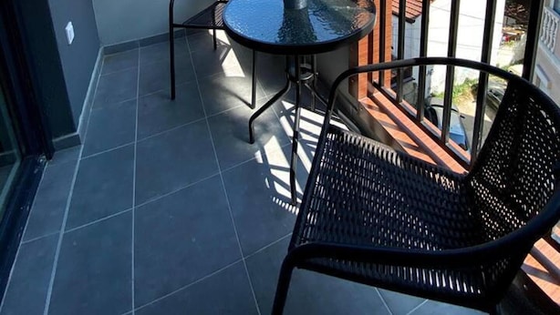 A balcony with a small table and two chairs, an air conditioning unit, and a view of the cityscape. - Brand new 2 Bedroom Apartment in the Center Skopje (Skopje)