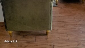 Una sala de estar con sofá, reposapiés y sillón, un tapete, y vistas de la ciudad a través de amplias ventanas.