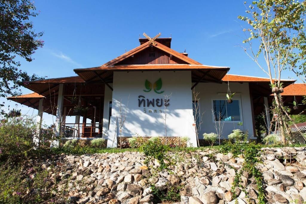 A building with a white facade and a brown roof, featuring a logo with green leaves and text.