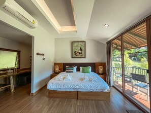 A spacious bedroom with a large bed, a television, and a balcony with outdoor furniture.