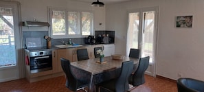 A kitchen with a dining table, chairs, a coffee maker, and a microwave.