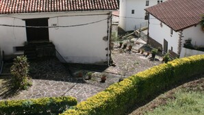 Un village traditionnel aux bâtiments aux toits de tuiles en terre cuite, aux chemins de pierre et à la végétation luxuriante.