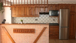 Une cuisine avec des meubles en bois, un réfrigérateur en acier inoxydable et un mur décoratif en briques sur lequel est accroché un panneau.