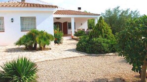 A two-story house with a covered porch, gravel driveway, and various shrubs and plants. - SAONA VILLAS (VN SILKA): villa 6 people, private pool, wifi (L'Ametlla de Mar)