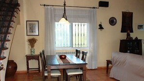 A dining area with a wooden table and chairs, a hanging light fixture, and a window with curtains. - SAONA VILLAS (VN SILKA): villa 6 people, private pool, wifi (L'Ametlla de Mar)
