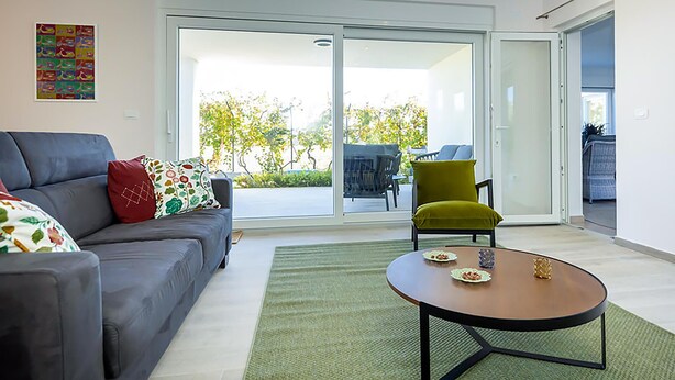 A modern living room with a grey sofa, a green armchair, and a round coffee table.