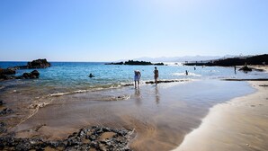 Una playa con zonas rocosas y agua azul cristalina.