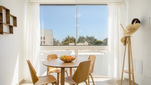 A dining area with a round table, four wooden chairs, a fruit bowl, and a straw hat on a stand. - Orange Volcano • Pool and Gym • Beach 1 min • LVH (Puerto del Carmen)