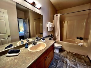 A bathroom with a double sink, a toilet, a bathtub, and a shower curtain. - Alpine Retreat: 2BR Ski-In/Ski-Out Condo with Private Hot Tub (Kimberley)