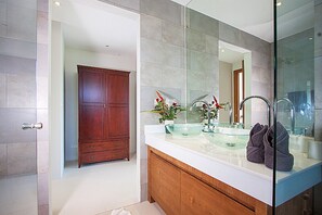 Ein modernes Badezimmer mit einer gläsernen Duschkabine, einem Holzwaschtisch mit Glasbecken und einem großen Spiegel.