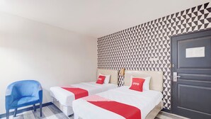 Een hotelkamer met twee bedden, een blauwe stoel en een behangen muur.