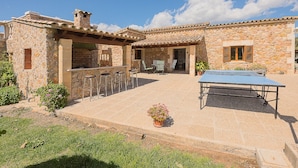 A stone building with a patio, outdoor seating, and a ping pong table.