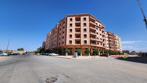 A multi-story apartment building with balconies, a parking lot, and a clear blue sky. - Résidence Belle Vue 6  (Marrakech)