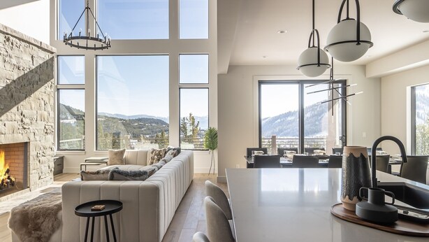 A modern living room with a fireplace, large windows, and a view of mountains.