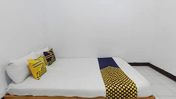 A bed with a wooden frame, white bedding, and two decorative pillows with geometric patterns.