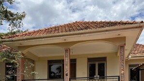 Una casa con techo de tejas, pared de piedra y patio empedrado.