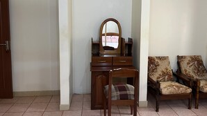 Una habitación con un aparador de madera, un espejo y dos sillones tapizados.